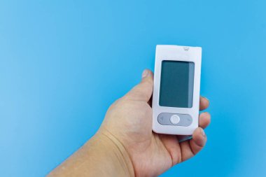 Kadınlardaki dijital glukometre, pastel mavi arka planı uzatıyor. Diyabet kavramı