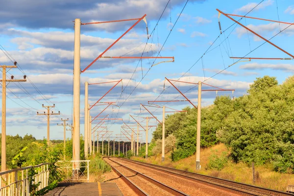 Kırsal alanda manzaralı demiryolu ve yazın beyaz bulutlu mavi gökyüzü.