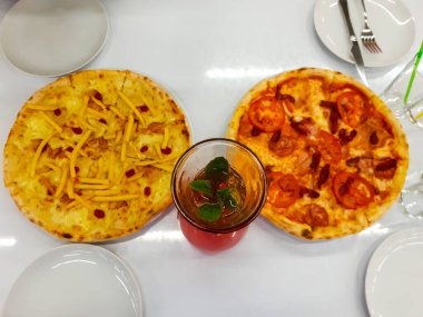Kafedeki bir masada iki pizza ve bir şişe çilekli limonata. Üst görünüm