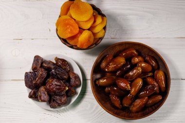 Kurumuş kayısılar ve beyaz ahşap masada meyveler. Üst görünüm