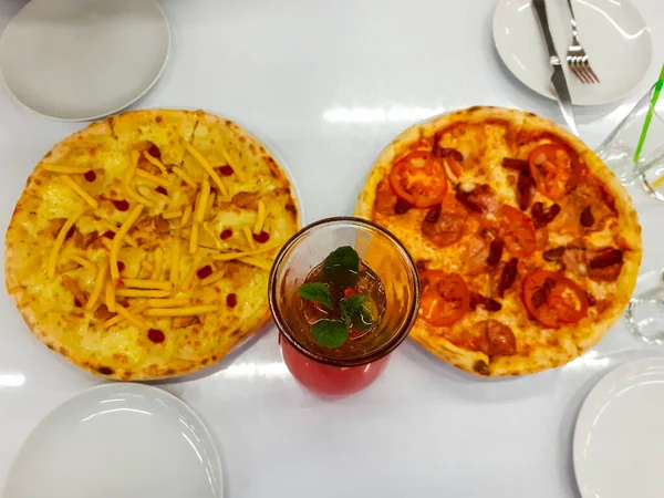 Kafedeki bir masada iki pizza ve bir şişe çilekli limonata. Üst görünüm