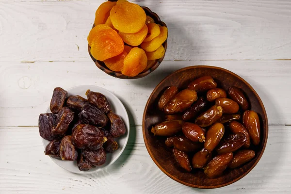 Kurumuş kayısılar ve beyaz ahşap masada meyveler. Üst görünüm