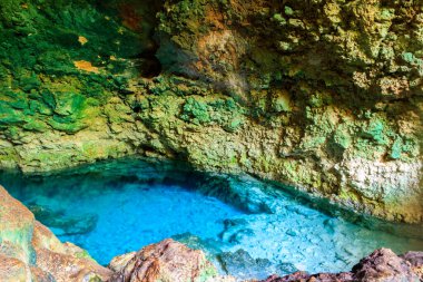 Kayalık bir mağarada dikitler ve dikitlerle oluşmuş güzel bir kristal berrak su havuzu manzarası. Tanzanya, Zanzibar 'daki Kuza mağarası