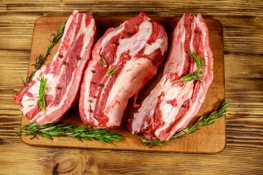 Baharatlı çiğ domuz pirzolası ve ahşap masada biberiye. Üst görünüm