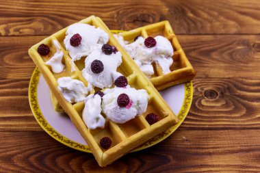 Dondurmalı Belçika waffle 'ı ve ahşap masada böğürtlen.