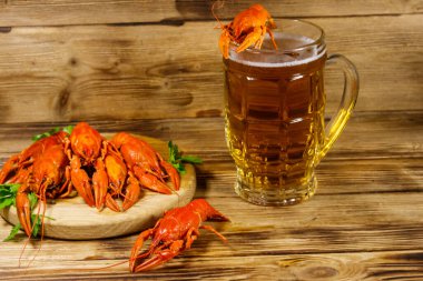 Haşlanmış kerevit ve bir kupa bira ahşap masada.