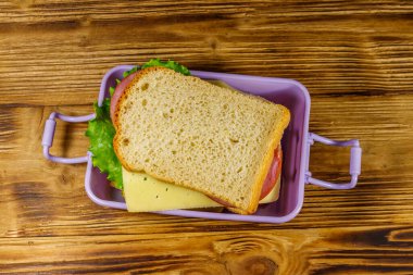Tahta bir masanın üzerinde sandviçlerle beslenme çantası. Üst görünüm