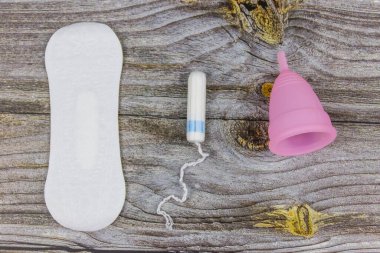 Tahta arka planda hijyenik ped, tampon ve regl kupası. Üst Manzara. Kritik günler, regl dönemi, kadın hijyeni