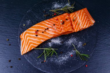 Çiğ somon fileto ve siyah tahta üzerinde baharat. Üst görünüm