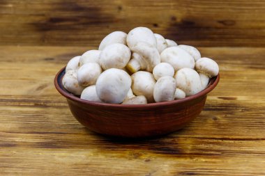 Tahta masada seramik kasede taze şampiyon mantarları.