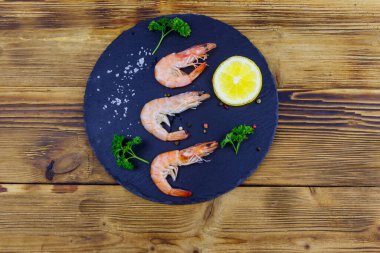 Tahta tahtada limonlu, maydanozlu, tuzlu ve biberli büyük çiğ karidesler. Üst görünüm