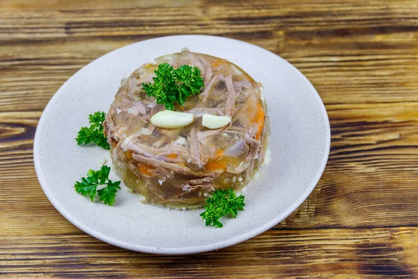 Meat aspic in a plate on a wooden table. Traditional russian dish