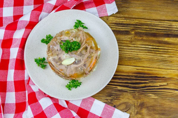 Meat aspic in a plate on a wooden table. Top view. Traditional russian dish