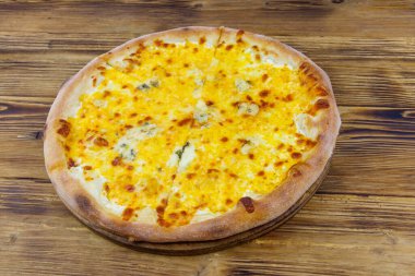 Tahta arka planda dört peynirli pizza.