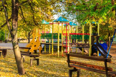 Colorful playground equipment for children in public park at autumn