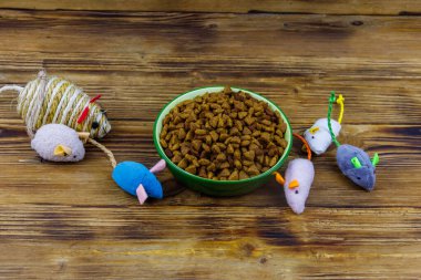 Kedi ve kase için tahta arka planda kuru hayvan mamasıyla fare oyuncakları. Hayvan bakımı konsepti