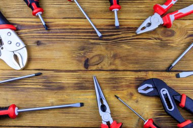 Tahta arka planda farklı pense ve tornavidalar var. Üst görünüm, alanı kopyala