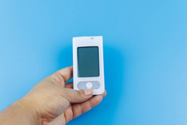 Kadınlardaki dijital glukometre, pastel mavi arka planı uzatıyor. Diyabet kavramı