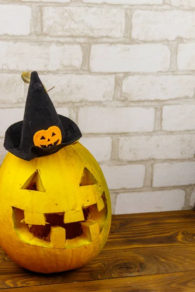Spooky Halloween pumpkin jack-o-lantern in witch hat on a wooden background