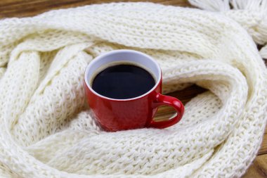 Etrafında beyaz örülü eşarp olan bir fincan kahve. Kış konsepti