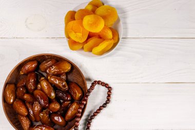 Kurumuş kayısılar ve beyaz ahşap masada ahşap tespihli meyveler. Üst Manzara. Müslümanların kutsal Ramazan bayramı
