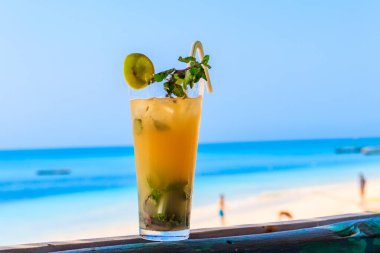 Okyanus kenarında bir bardak taze portakallı mojito kokteyli.