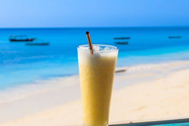 Okyanusun kenarında bir bardak taze meyve suyu. Tropik tatil kavramı