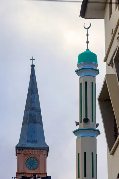 Christian church and minaret of the mosque side by side in Stone Town, Zanzibar, Tanzania