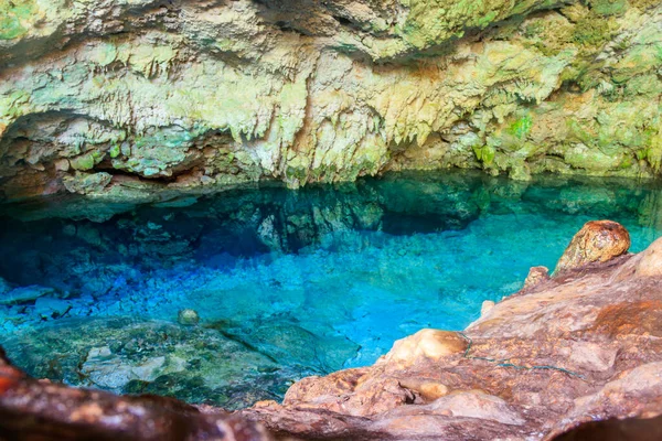 Kayalık bir mağarada dikitler ve dikitlerle oluşmuş güzel bir kristal berrak su havuzu manzarası. Tanzanya, Zanzibar 'daki Kuza mağarası
