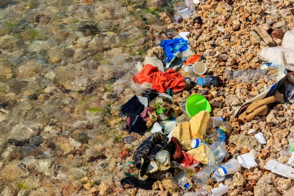 Garbage on a bank of ocean. Pollution of sea, ocean water with waste, plastics garbage. Concept of pollution of ocean, sea and river coastline with plastic trash