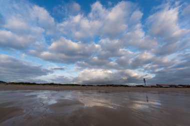 Gökyüzü kara bulutlarla kaplı ve kumsal bulutlu.