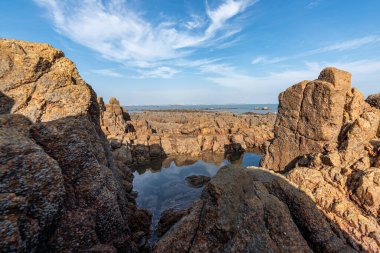 Deniz kenarındaki resifler arasındaki deniz suyu Sarı resifleri ve mavi gökyüzünü yansıtır.