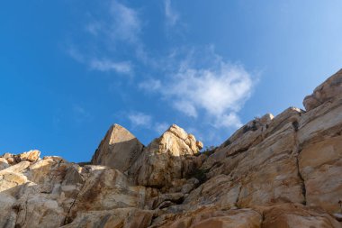 Mavi gökyüzünün altında deniz tarafından yıpranmış çeşitli şekillerde taşlar.