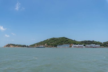 Mavi gökyüzü ve beyaz bulutların altında deniz ve kıyı şeridi