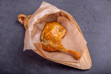 Konteynırdaki marine edilmiş sarı tavuk bacakları koyu bir arka planda.