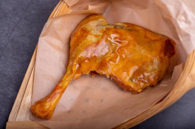 Konteynırdaki marine edilmiş sarı tavuk bacakları koyu bir arka planda.