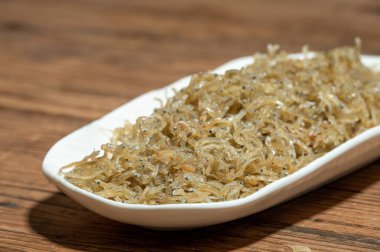 Konteynırdaki kurutulmuş karanfil balığı ahşap tahıl masasının üzerinde.