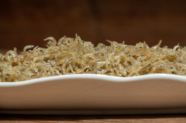 Konteynırdaki kurutulmuş karanfil balığı ahşap tahıl masasının üzerinde.