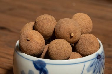 Tahta tahıl masasının üstündeki konteynırda kurumuş Longan.