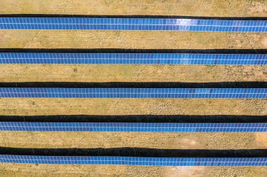 Güneş tarlası hava manzarası, küçük bir evin yanındaki sıra sıra PV panelleri.