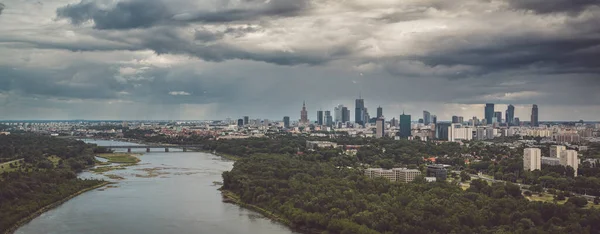 Moody sky over distant skyline of Warsaw city center and Vistula river aerial landscape