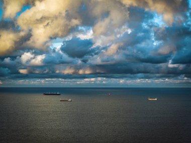 Deniz körfezinde yüzen konteynır gemilerinin karamsar gökyüzü, alacakaranlıkta havadan manzara