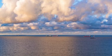 Deniz körfezinde yüzen konteynır gemilerinin karamsar gökyüzü, alacakaranlıkta havadan manzara