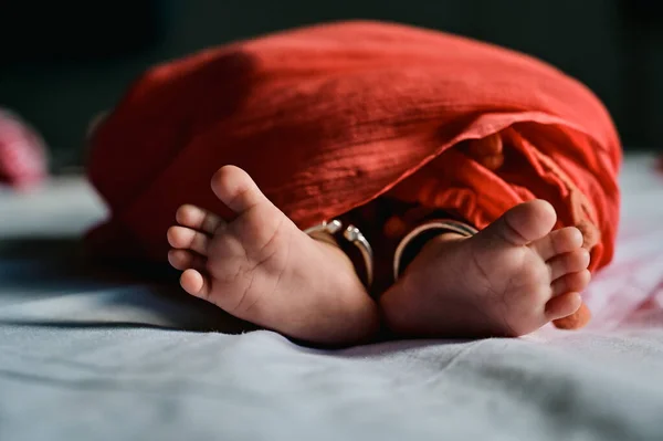 Indian Newborn baby feet in red cloth blanket. Happines and Peaceful