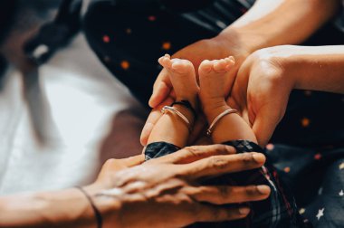 Mother Hands Holds Baby Legs. Lovely moment of mother and baby. Indian Baby Legs. Legs with small anklets and black thread.