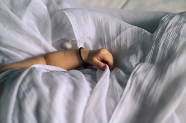 Small Baby hand holding white blanket. Lovely Baby hand with black thread as blessing god protection. Indian Newborn baby. White Cloth 
