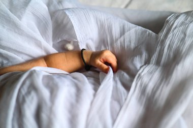 Small Baby hand holding white blanket. Baby hand with black thread as blessing god protection. Indian Newborn baby. White Cloth 