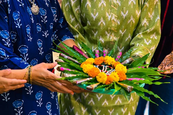 Lovely Mehendi Tube and Flowers In Woman Hands. Elegant Mehendi Ceremony  Party Celebrations. Event With Marigold flowers and green leaves decorations. Indian Traditional Event