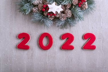 Mutlu yıllar 2022. Kırmızı zencefilli kurabiye ve Noel çelengi. Arkaplanda açık gri duvar.