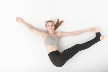 Genç kadın jimnastik yapıyor. Esnekliğin gelişimi. Yogadaki Asanas. Güzel ince kız beyaz arka planda hatha yogası yapıyor..